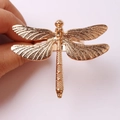 Golden dragonfly napkin ring with intricate mesh wings shown in a hand-held view - Twill Dragonfly