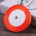 Bright orange satin ribbon roll for gift wrapping and hair accessories on wood floor - Orange Red