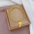 Detail van de gouden vossenhanger aan kralenarmband op een elegante zijden achtergrond - Goud