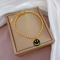 Makroansicht der goldenen Perlenarmband mit schwarzem Smiley-Anhänger auf Schmuckschachtel - Goldfarbener Perlenstil Mit Schwarzem Emaille Smile Face (K335黑金)