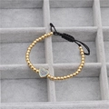 Detalle de pulsera tejida con cuentas doradas y colgante de corazón de circón azul - Dorado