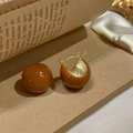 French vintage caramel hoop earrings with gold metal accents on a book background - Caramel Circular Ear Buckle