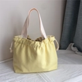 Detail of light yellow canvas tote bag with drawstring closure and cream cotton handles - Light Yellow