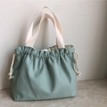 Detailed texture of thick sage green canvas handbag with drawstring and woven handles - Haze Blue