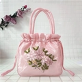 Detailed shot of pink satin bucket bag featuring intricate 3D ribbon floral embroidery - Pink