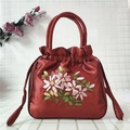 Detailed close-up of red satin bucket bag with intricate floral embroidery and drawstring - Burgundy