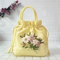 Detail of yellow satin bucket bag featuring intricate ribbon embroidery and drawstring - Yellow
