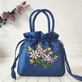 Close-up of blue satin bucket bag featuring intricate floral embroidery and drawstring - Sapphire Blue
