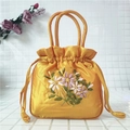 Detail of yellow satin drawstring bag with elegant ribbon flower embroidery and handles - Orange