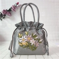 Detailed close-up of ribbon floral embroidery on silk satin drawstring handbag - Gray