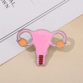 Primer plano de un pin esmaltado del sistema reproductivo femenino con acabado en rosa - Órgano Reproductor Femenino / Rosa