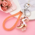 Gros plan du porte-clés dinosaure irisé avec sangle tressée et fermoir en métal argenté - Boucle Argentée + Dinosaure + Sangle en Strass / Orange
