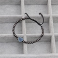 Detalle de dije de corazón con circón azul en pulsera de cuentas en caja de terciopelo - Color gunmetal