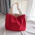 Detail of red drawstring canvas tote bag with cream handles on white fabric - Watermelon red