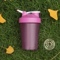 Detail of purple protein shaker bottle with mixing whisk ball on grass background - Purple