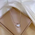 Dettaglio ravvicinato di una collana a cuore argento su una scatola di gioielli beige - Argento
