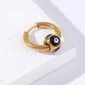 Detailed close-up of golden stainless steel hoop earring with black and white evil eye charm - Gold-Black