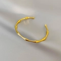 Eleganter goldener Armreif im Bambus-Design für Damen auf grauem Seidenstoff - Gold