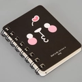 Close-up of black A7 spiral notebook featuring pink cartoon art and English quote - Expression-Black