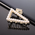Macro shot of triangular gold hair claw with white pearls reflecting on a mirror - Gold Full Pearl Triangle Claw Clip