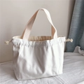 Dettaglio della borsa tote in tela bianco avorio con chiusura a coulisse e manici robusti - Bianco