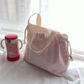 Detail of pink drawstring canvas tote bag with cotton tassels on a bright windowsill - Pink