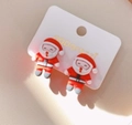 Close-up van Kerstman oorbellen van hars op een witte kaart met warme feestelijke verlichting - Stijl 3 Kerstman Clip