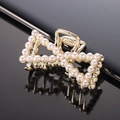 Close-up of golden bow hair claw clip with white faux pearls on black reflective surface - Gold Full Pearl Bow Claw Clip