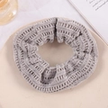 Close-up of a grey knitted velvet scrunchie on a beige tray with elegant aesthetic props - Khaki