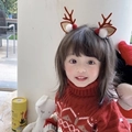 Close-up of a child wearing plush reindeer antler headbands with festive red decorations - Brown Antlers with Pom Pom Ears Pair