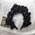 Dettaglio del cerchietto in raso nero con texture a pieghe lucida e tessuto effetto seta - Nero
