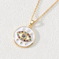 Macro detail of golden evil eye pendant with colorful zircon stones on white leather - Style L-Triangle Decor Colorful Eye