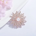 Détail d'une broche fleur or rose avec strass brillants et une grande perle centrale - Or Rose Tournesol
