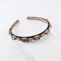 Detailed shot of retro headband with gray crystals and pearls on white stone - Black