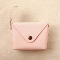 Close-up of pink macaron coin purse with bronze buckle on woven fabric background - Light Pink