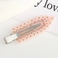 Detailed macro view of a pink flower hair clip featuring faux pearls and rhinestones - Pink