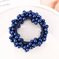 Detail of navy blue beaded elastic hair tie with lustrous faux pearls on a ceramic dish - Blue