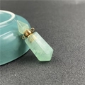 Close-up of green crystal perfume bottle pendant with golden hexagonal prism detail - Fluorite