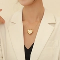 Elegant gold heart pendant necklace for women worn with a stylish white blazer - Gold