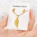 Nahaufnahme des goldenen Edelstahlschmucksets mit stilisiertem Flügelanhänger und Ohrringen - Flügel