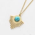 Detailopname van de gouden zonnehanger met turquoise steen op een fijne ketting - Meer blauw