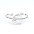 Macro shot of silver wire wrapped tree of life on heart crystal on a flexible bangle - Natural / White Crystal