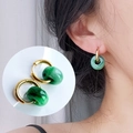 Close-up of 18k gold-plated hoop earrings with dark green natural stone pendant charm - Gold-Faux Jade