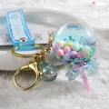 Lollipop liquid keychain with colorful beads and Sakura strap on white plush surface - Blue
