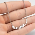Silver bird on tree branch pendant necklace held in hand showing delicate details - Three Birds Silver