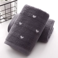 Deep grey cotton towel with white heart pattern stacked neatly by a black basket - Dark Gray