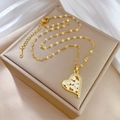 Eleganter goldener Herzanhänger mit kleinen Kristallen auf einer cremefarbenen Box - Goldener Herz Emaille Anhänger