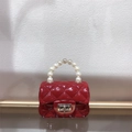Detail of a red mini jelly bag with quilted texture, pearl handle and turn-lock closure - Burgundy
