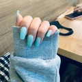 Primer plano de uñas postizas estilo ballerina azul claro mate sobre una manga gris - Azul claro