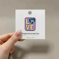 Macro shot of an enamel Love Earth pin with a heart globe on a white display card - Heart Earth (Love)